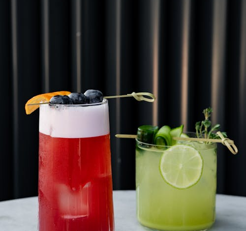 Two cocktails with lime and blueberries on a table - Pexels Kadir Avşar